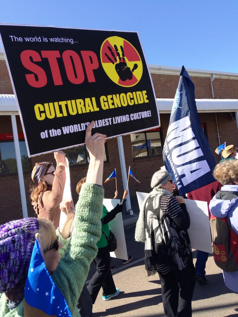 Anti nuclear protestor holds sign reading:"Stop cultural genocide of the world's oldest living culture"