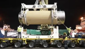 A large barrel is being loaded onto a truck with a crane.