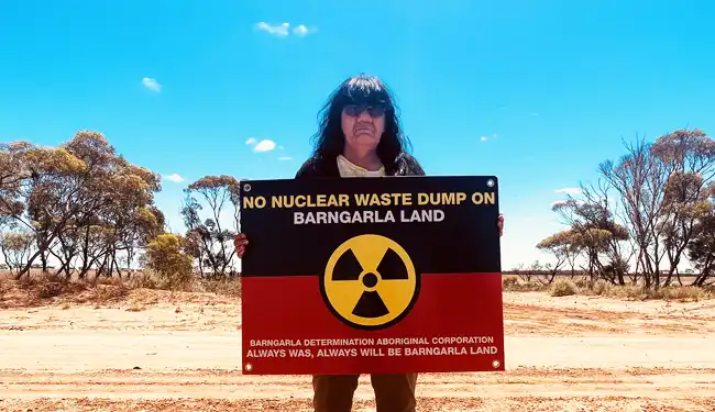 Barngarla woman Dawn Taylor holds up a sign on her country, it reads no nuclear waste dump on Barngarla land