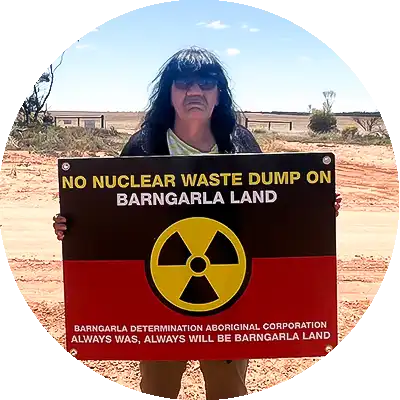 Barngarla woman Dawn Taylor holds up a sign on her country, it reads no nuclear waste dump on Barngarla land