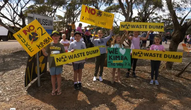 Group of kids holding up placards against the waste dump, Kimba
