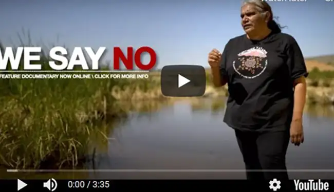 Aboriginal woman stands in mound Spring - Still from we say no